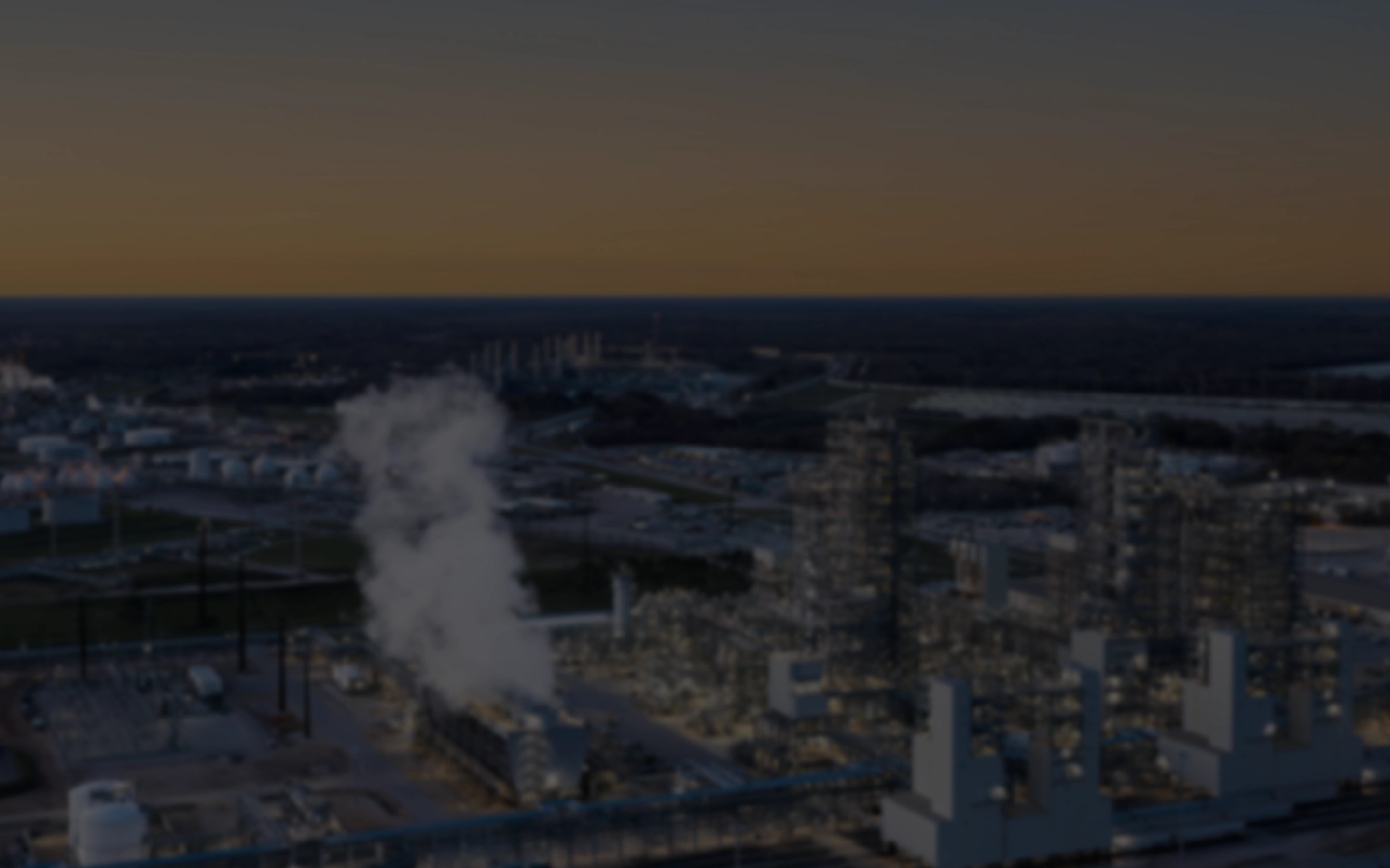 Bird-view on a industrial city at night with white vapor rising from one prominent buidling in the front (Photo)